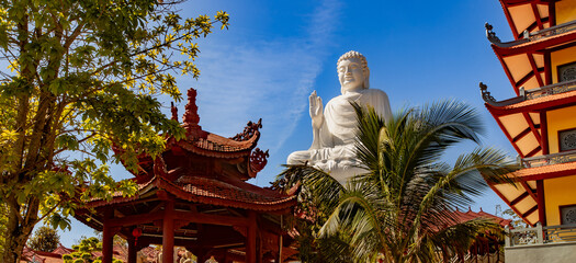 Buddha statue surrounded by pagodas, in peaceful meditation, at Chua Hue Chieu temple in Kontum, Vietnam, Panorama © Olga Khoroshunova