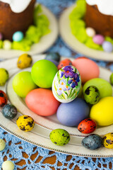 Easter traditional food for Russia: colorful painted Easter eggs, Eastre cakes, tradition Russian cottage cheese dish called Easter with chocolate on laid table with blue lace tablecloth