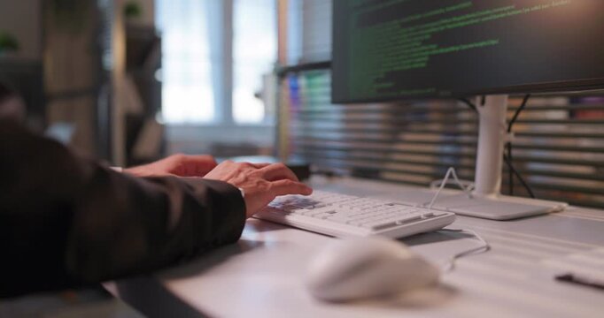 Developer programmer hands typing coding on computer keyboard. Close view shows code on screen in office, conveying speed and productivity for tech tasks. Sharp concept of software coding work.