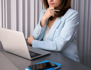 Business woman working on laptop at desk in the office. Professional female manager planning tasks, analyzing information, corporate work routine, focus and productivity.