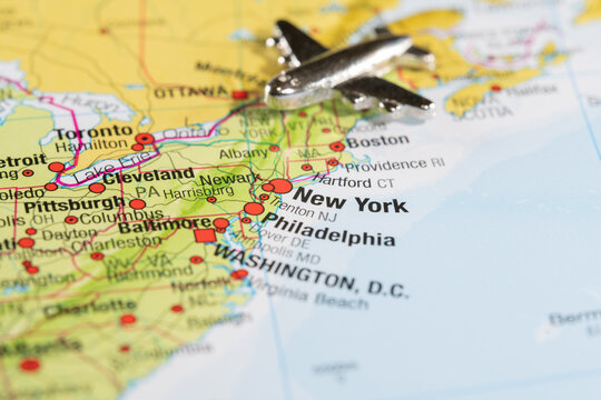Silver airplane model placed on a map of the United States, focusing on the East Coast