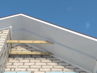 Roof eaves with wooden beams under construction against clear blue sky background