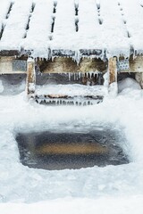 Fototapeta premium Hole in a frozen lake with frozen ladder and wooden pier covered in snow ready for cold therapy, ice bathing. Wim Hof Method, cold therapy, breathing techniques