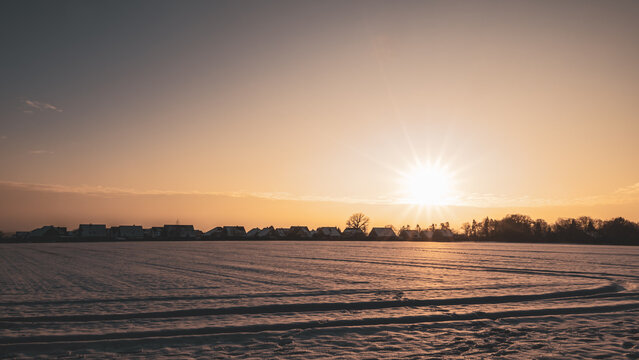 Bramsche outskirts at Bramscher Berg in winter sunset light, snowy field foreground and distant houses on the horizon