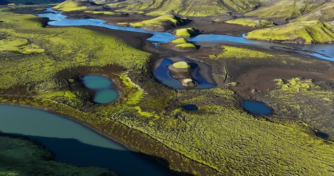 Drone glide over Icelandic highlands showing braided channels, blue lagoons and mossy lava plains under clear summer sky&mdash;vast remote wilderness landscape.