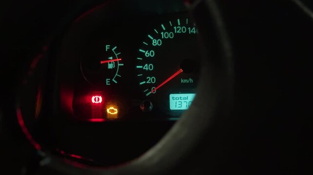 Closeup of car dashboard featuring active warning icons and needle positions under soft lighting