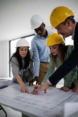 Multiethnic team discussing construction blueprints wearing hard hats