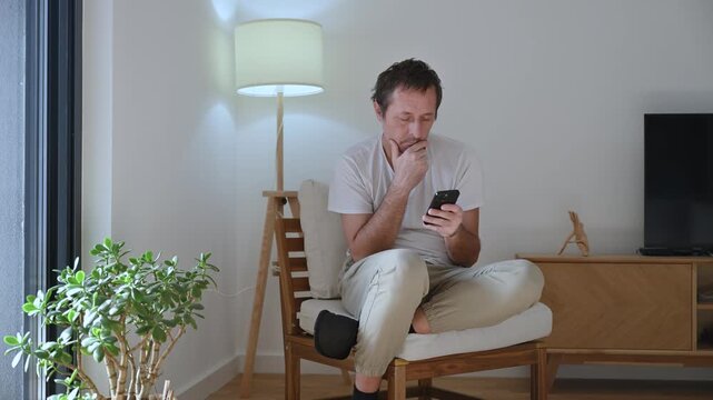 Dull idle mature man wasting time doom-scrolling on smartphone, procrastinating and disengaged while browsing aimlessly. 4K.