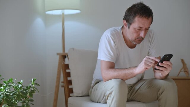 Bored adult male distracted and idle on phone, doom scrolling and procrastinating with blank expression and low energy mood. 4K.