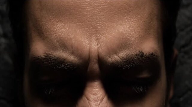 A dramatic close-up focuses on a man's forehead and eyes as his expression shifts. He slowly moves from a mild furrow to an intense scowl, creasing his forehead deeply, before gradually relaxing the 