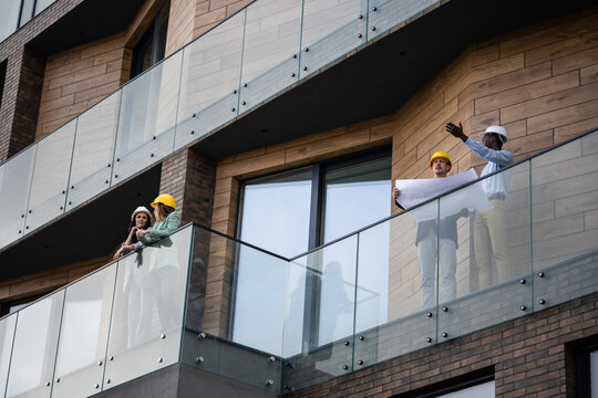 Engineering team discussing building construction blueprints on balcony