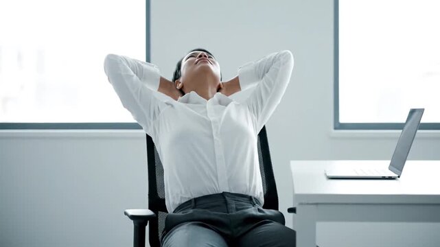 An office worker takes a quick wellness break, leaning back in their chair to stretch their neck and body, hands behind their head, releasing tension, and smiling after feeling relaxed and refreshed.