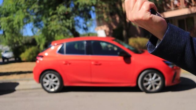 Selling a used red car outdoors in daylight. Female and male hands exchange car keys, symbolizing vehicle sale, ownership transfer, successful agreement or car delivery by car rental