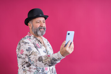 Mature man wearing bowler hat using smartphone
