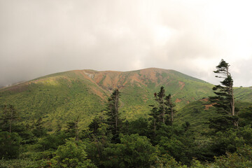 夏の草津白根山、荒々しい火山の山肌と背後に湧き上がる雲