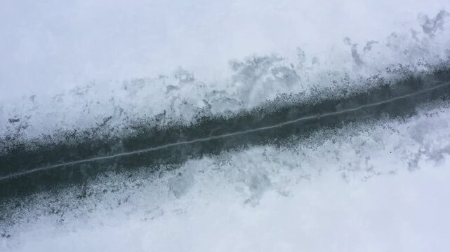 A pressure ridge forms on a frozen lake, allowing lake water to seep up to the surface layer of ice, melting the powdered snow on top. 