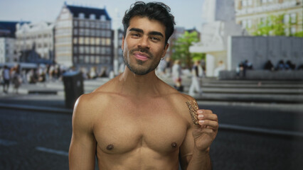 Obraz premium Shirtless man holds granola bar near face under golden sunlight on urban street square; satisfaction.