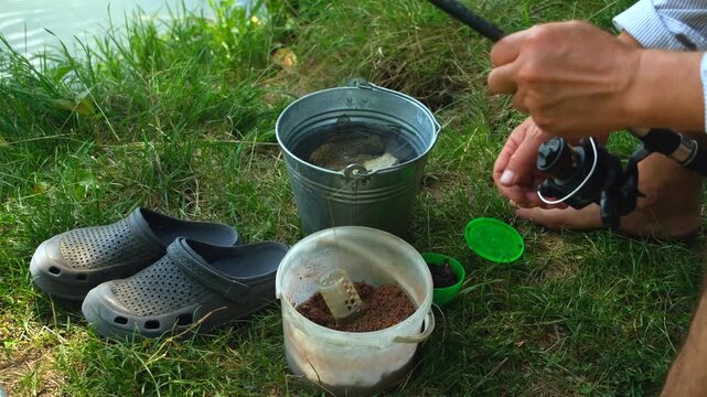 Close-up of Fisherman Hands Preparing Bait on River Bank with Fresh Catch