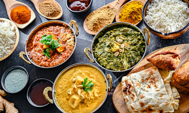 Composition with indian dishes: madras paneer, palak paneer and shahi paneer with basmati rice served in original indian karahi pots