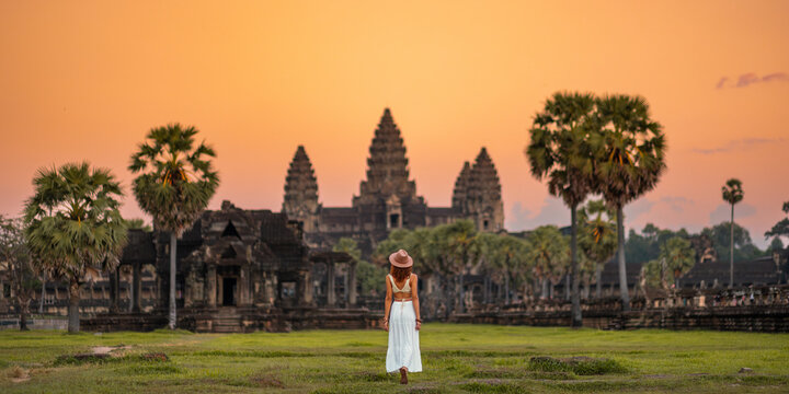 Woman in White Dress Walking Toward Angkor Wat Temple at Sunset, Cambodia