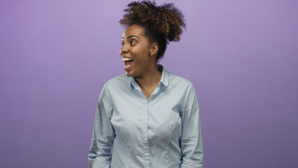 Woman laughing with open mouth and visible face, turning head to the left and gesturing with one hand in purple studio; joy optimism.
