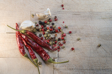 Chili peppers and spices arranged on a wooden board for cooking preparation in a kitchen setting