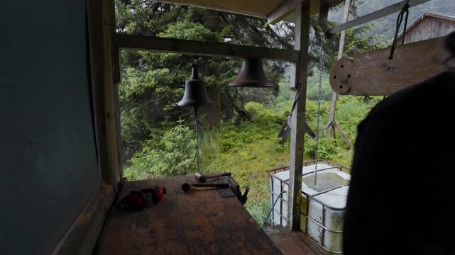 Orthodox christian priest walking away from church bells at a secluded monastery in alaska