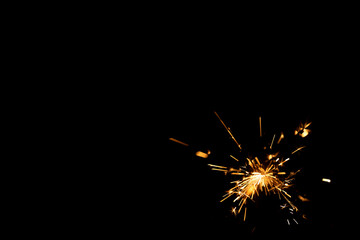 Fototapeta premium Sparkler emitting bright sparks against a dark background, showcasing individual sparks radiating outward in various directions, creating a dynamic visual effect