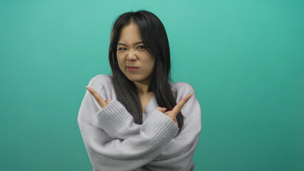 Fototapeta premium Woman pointing with hands in different directions against an isolated green background wall, expressing indecision or confusion.