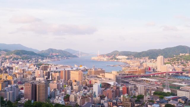 Nagasaki, Japan. Aerial timelapse made from a hill in Nagasaki, Japan, with a view over the entire center, including the bay and the hills. Cloudy and sunny day in summer, zoom in