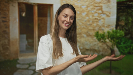 Naklejka premium Woman in white t shirt giving thumbs up at building entrance, smiling directly to camera; happy welcome.