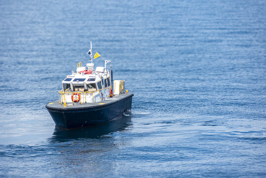 Small pilot vessel navigating over smooth blue sea in daylight.