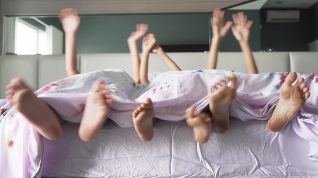 Happy Family Waking Up Together: Feet and Hands Wiggling Under Blanket in Bed