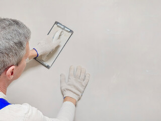 Close up view the hand of a worker and a tool for grinding putty.