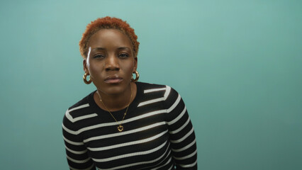 Woman tilts head revealing face with closed eyes and hoop earrings in striped top in studio  calm introspection. © Krakenimages.com