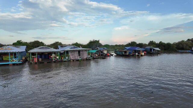 scenic tour on Tonle Sap lake, Cambodia &mdash; floating houses, calm waters, partly cloudy sky, viewed from excursion boat