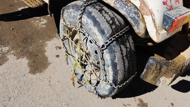 snow chains installed on car tire for icy mountain roads