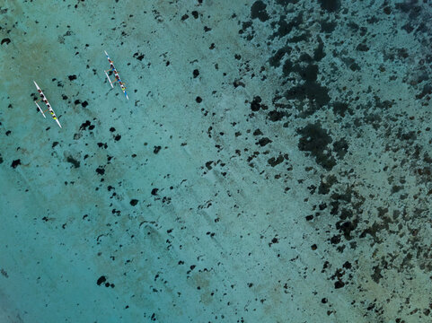 Aerial view of kayaks gliding across the turquoise waters with dark seabed patterns adding contrast, Guam, United States.