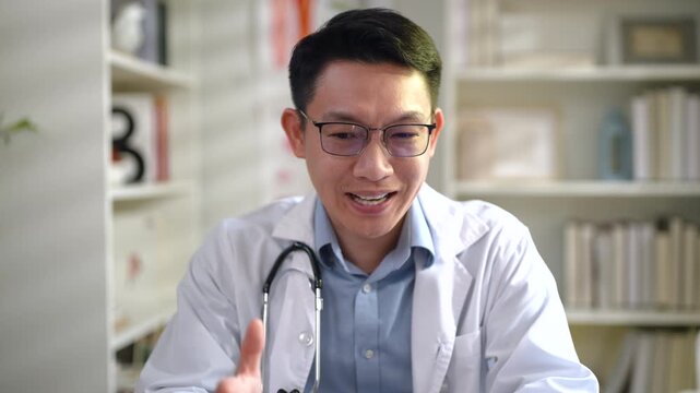 Close up portrait of a confident Asian male doctor speaking and explaining diagnosis during a virtual medical consultation through camera view.