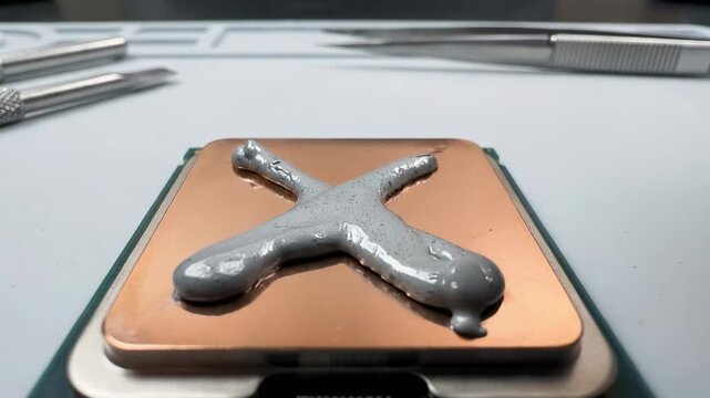 A technician applies thermal paste to a CPU in a precise cross pattern using a syringe applicator. This technique ensures optimal heat transfer for improved cooling efficiency in computers