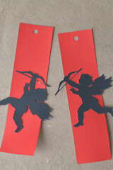 silhouettes of cherubs with bows on red paper tags