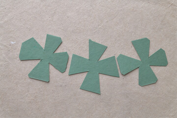 abstract cut green paper cruciform shapes on brown