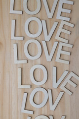 the word love composed with wooden letters repeated on a pine surface