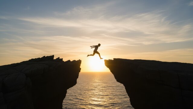 A brave man takes a bold leap of faith jump between cliffs at sunset to achieve his ultimate success.