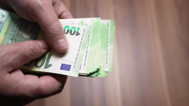 Extreme Close-Up of Euro Notes. Extreme close-up of 100 euro banknotes being counted by fingers. Focus on texture, security features, and cash detail.