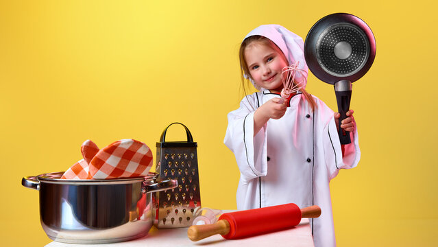Young girl chef holding pan and whisk in studio. Concept of cooking education, playful food learning, childhood profession dreams, creative development and culinary imagination.