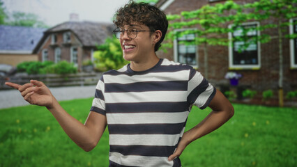 Fototapeta premium Teenage boy pointing hand and smiling with glasses and striped t shirt in building; joyful youth energy.