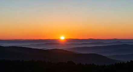 Fototapeta premium Breathtaking sunset over layered mountains with vibrant orange sky