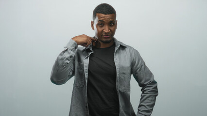 Fototapeta premium Man pointing finger to camera with hand near neck, wearing black shirt in studio portrait; confidence direct challenge.