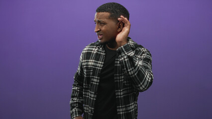 Young man holding a screwdriver, cupping his ear and tilting his head while listening in a studio...